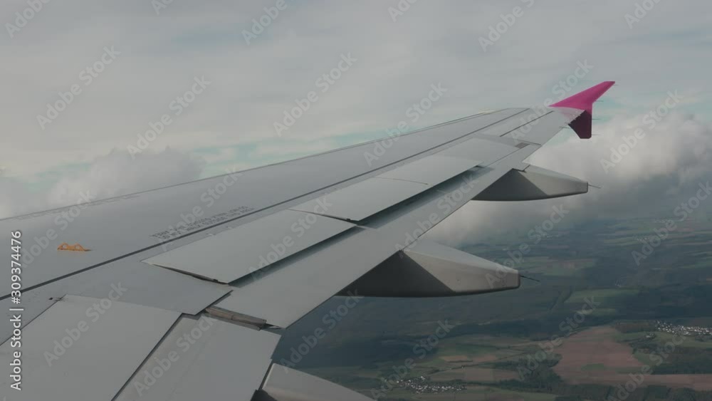 Awesome view from airplane window on fields, woods, green ground. Up in the sky there are white beautiful clouds near plane wing. Awesome view from airplane window on fields, woods, green ground. Up in the sky there are white beautiful clouds near plane wing.