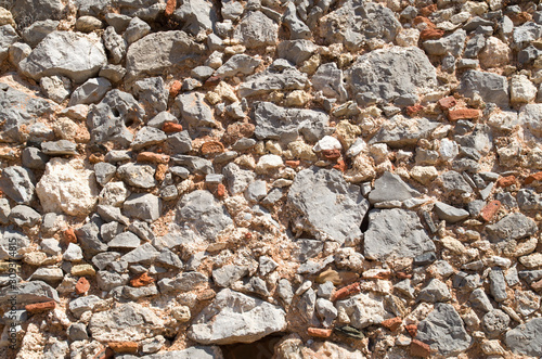 Colorful ancient stone wall with pieces of ceramics closeup