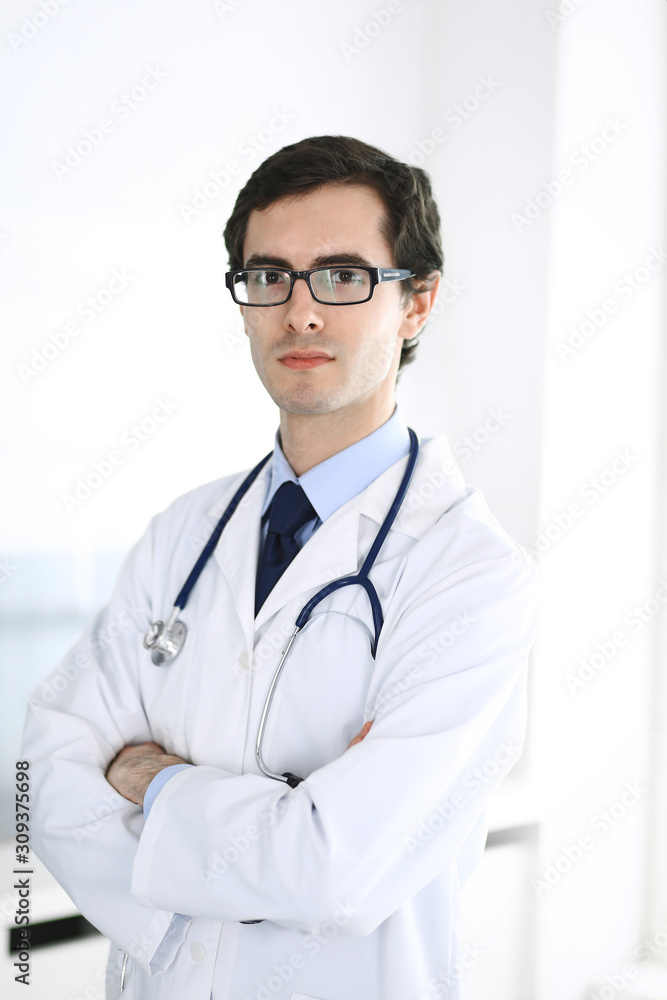 Doctor man standing straight with arms crossed. Perfect medical service in clinic. Happy future in medicine and healthcare Doctor man standing straight with arms crossed. Perfect medical service in clinic. Happy future in medicine and healthcare