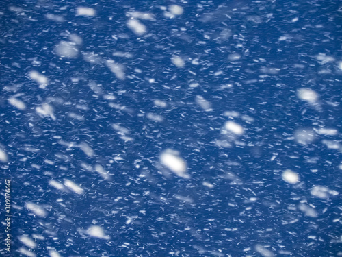 Snowstorm against the blue evening sky. Background, abstract texture. Motion blur, selected focus