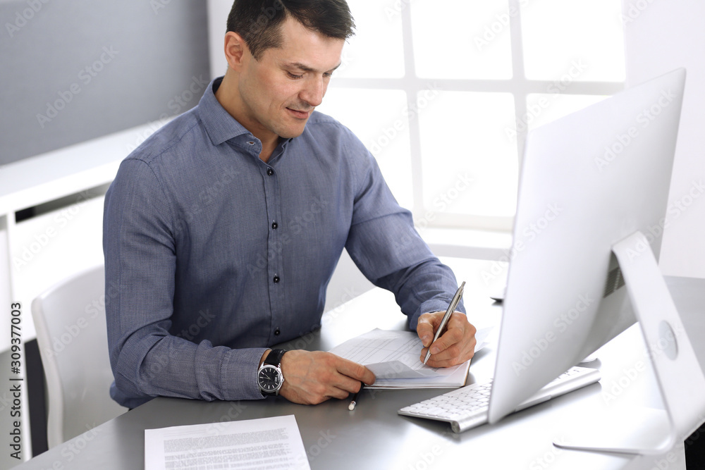 Fototapeta premium Businessman working with computer in modern office. Headshot of male entrepreneur or company director at workplace. Business concept