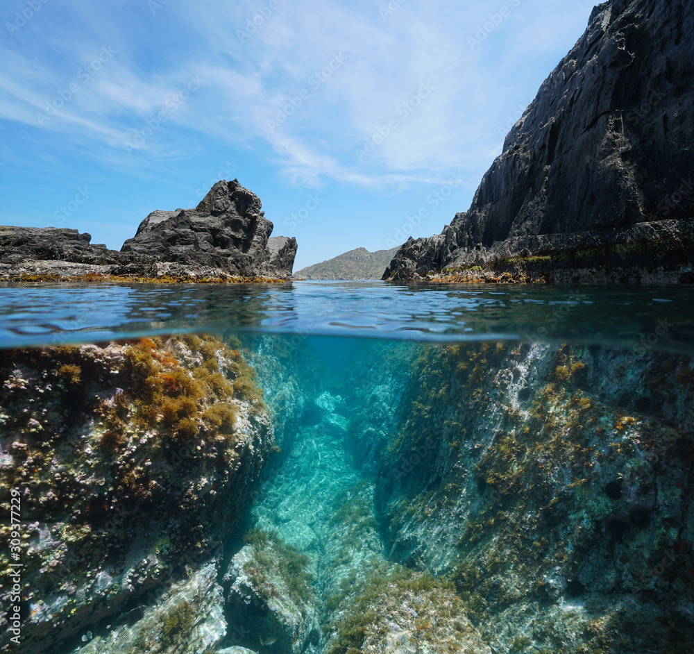 Rocky coast with a passage between rocks, split view over and under water surface, Mediterranean sea, Spain, Costa Brava, El Port de la Selva, Catalonia