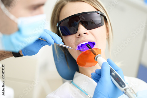 Stomatologist examines mouth of his patient with UV. Selective focus