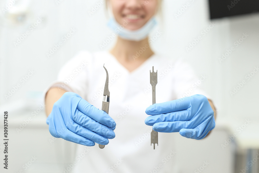 Attractive female dentist holds tools in her hands and smile charmingly. Selective focus Attractive female dentist holds tools in her hands and smile charmingly. Selective focus