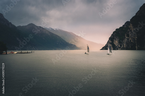 sale boat on calm water in lake Garda Italy, moody sky and golden sunset
