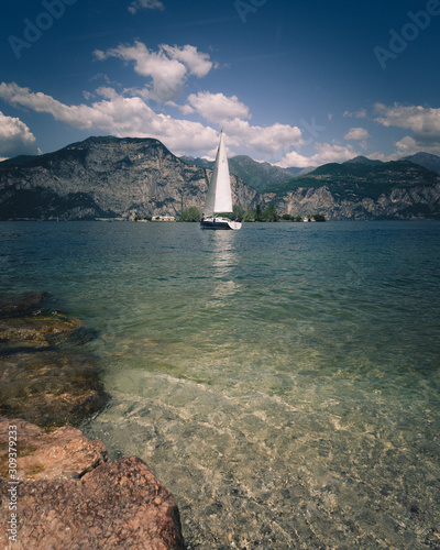 Lone yacht on lake Garda in Italy with the mountains in the background on calm waters