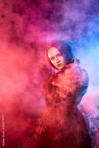 Portrait of chubby teen girl during photoshoot with colored smoke at night and black background