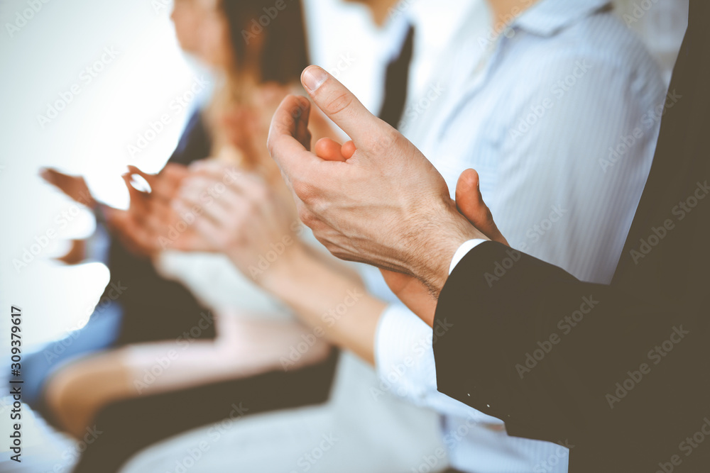 Obraz premium Business people clapping and applause at meeting or conference, close-up of hands. Group of unknown businessmen and women in modern white office. Success teamwork or corporate coaching concept