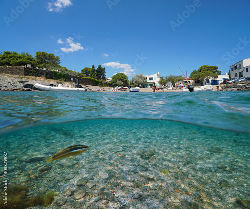 Spain Mediterranean sea summer vacation, cove with boats and tourists in the village of Cadaques, split view above and below water surface, Costa Brava, Catalonia