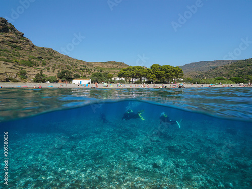 Spain, Cadaques village coastline with scuba divers underwater, Mediterranean sea, split view above and below water surface, Costa Brava, Catalonia