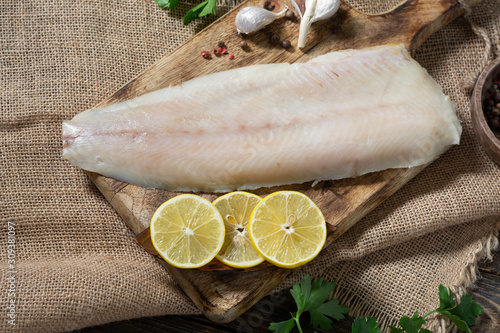 Whitefish lightly salted on a wooden Board on a brown wooden table. Whole fillet of fish whitefish or muksun closeup. Top view with space for text photo