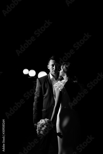 Fashionable newlyweds with electric bulbs at night. Night shooting of bride and groom