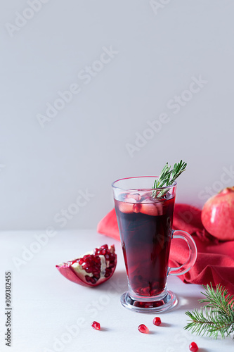 Pomegranate Christmas cocktail with champagne, soda and rosemary on a white table. Xmas drink.