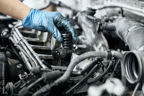 Professional mechanic checking nozzle in diesel car engine