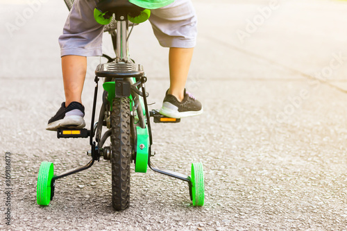 Learning to ride a bike concept, The little boy is practice to cycling a bicycle with the training wheels on the road. photo