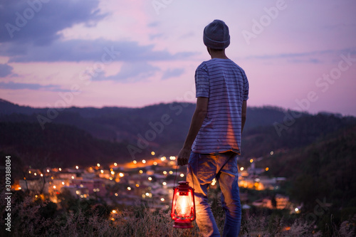 young man holding an old lantern to illuminate