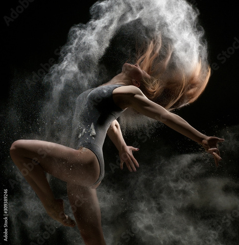 Fototapeta Naklejka Na Ścianę i Meble -  Girl dancing in a cloud of white dust studio portrait