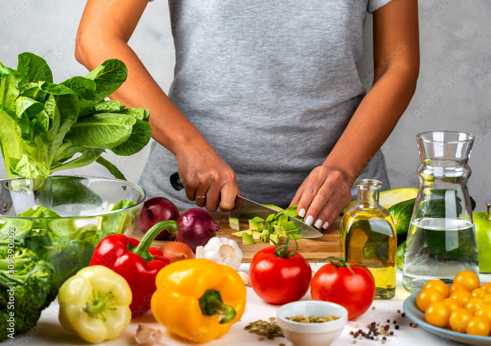 Woman cuts avocado and cooking salad in the kitchen. Healthy diet concept. Woman cuts avocado and cooking salad in the kitchen. Healthy diet concept.