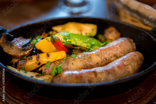 Grilled fried sausages kupaty on iron skillet grill with vegetables