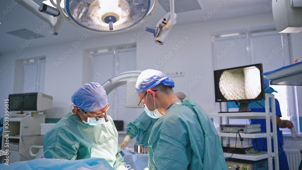 Surgery team operating in room. Surgeons team working with monitoring of patient Surgery team operating in room. Surgeons team working with monitoring of patient