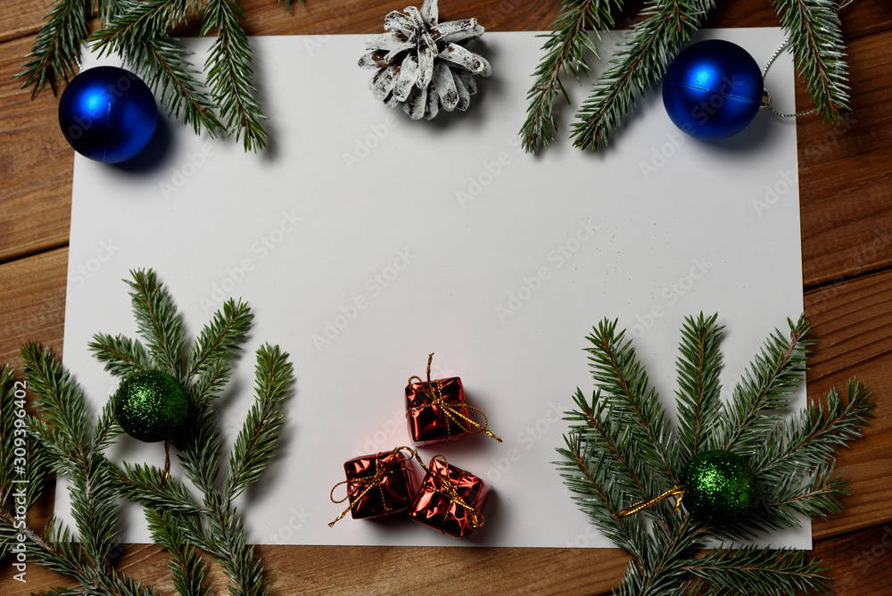Christmas decorations on a white background table with a blank white sheet. New Year's pine cones and New Year's balls. Place for text Christmas decorations on a white background table with a blank white sheet. New Year's pine cones and New Year's balls. Place for text