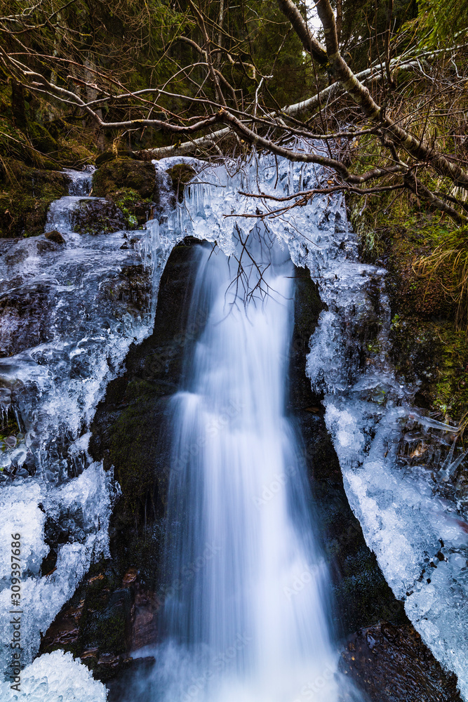 A small active waterfall. Clean mountain stream, snowy winter landscape, wildlife background A small active waterfall. Clean mountain stream, snowy winter landscape, wildlife background