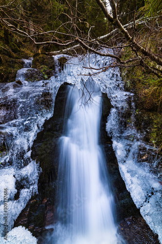 A small active waterfall. Clean mountain stream, snowy winter landscape, wildlife background
