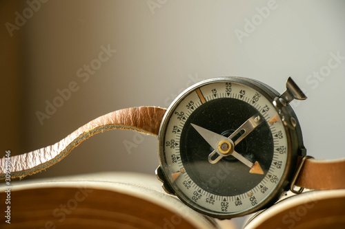 on an open old book a wrist compass with a leather strap