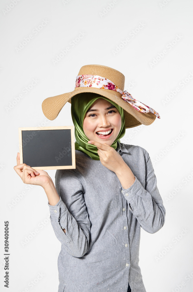 beautiful lady with hijab standing and holding blank chalkboard for text. smiling face ideal for advertising concept beautiful lady with hijab standing and holding blank chalkboard for text. smiling face ideal for advertising concept