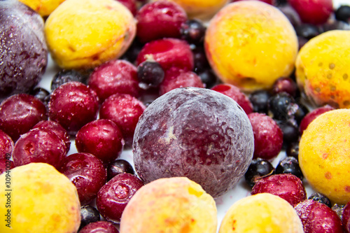 A Berry mix from frozen currant  apricot  plum  cherry. A Frozen Berries from freezer. A sweet background with frozen plum  currant  apricot and cherry. A healthy Berries on the background.