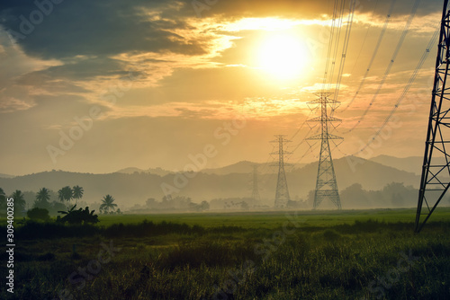 High voltage tower, Electric post and electric cable on the field in the countryside with in the morning sunrise background.