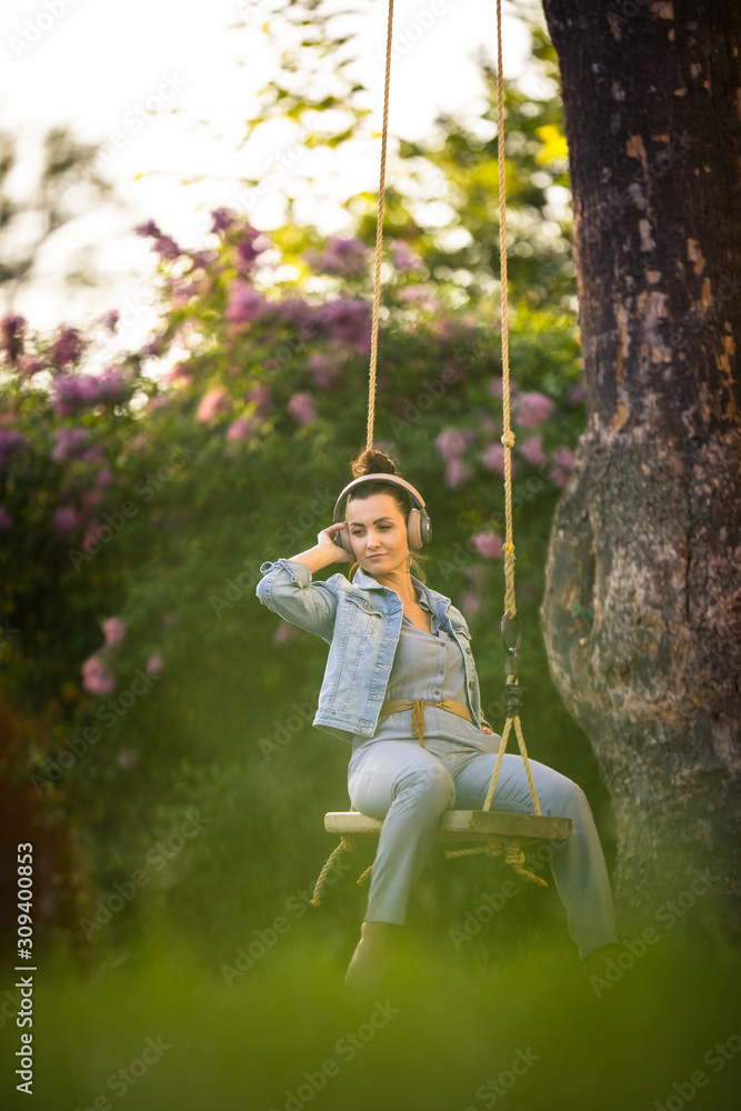 Pretty, young woman with headphones outdoors, in a lovely park, enjoyig the hi-fi quality sound, listening to her favorite songs (color toned image)