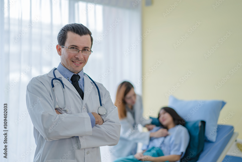 A professional doctor standing in a room with a patient lying in bed with an assistant doctor to prepare for a patient check up. A professional doctor standing in a room with a patient lying in bed with an assistant doctor to prepare for a patient check up.