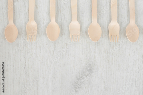 Brown wooden spoons and forks -cutlery lie on a white wooden table. Background. The concept of environmental protection, ecology plastic free, zero waste. Place for text