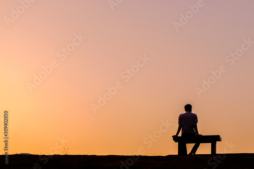 Silhouette man sitting on bench at golden hour, at Ang Kaew Reservoir, Chiang Mai University (Chiang Mai, Thailand)