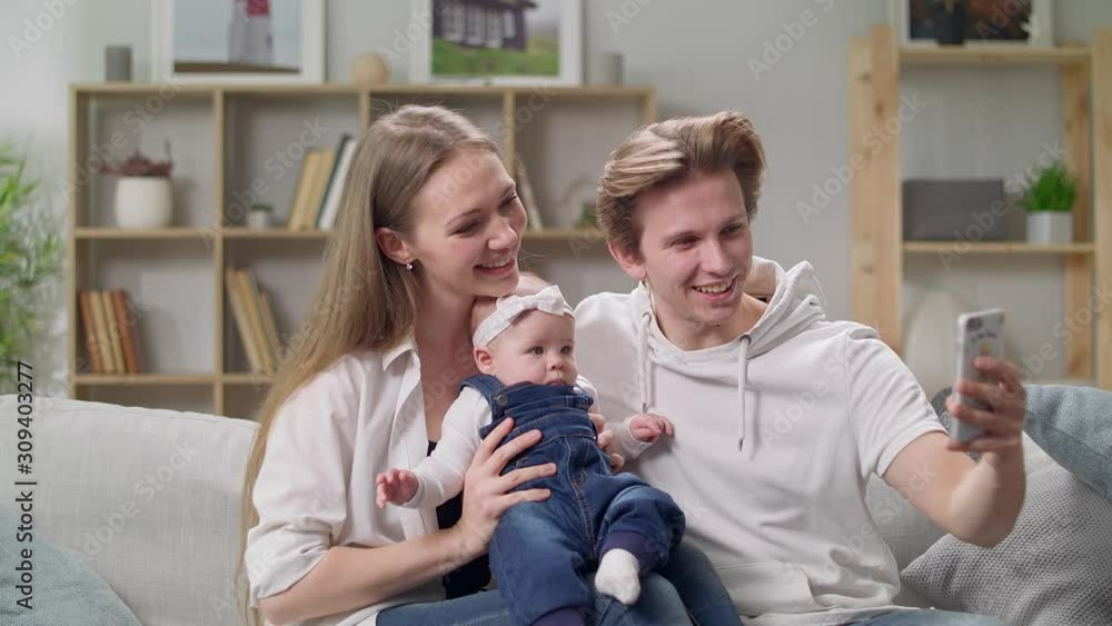 Young family taking a selfie on the sofa in the living room Young family taking a selfie on the sofa in the living room