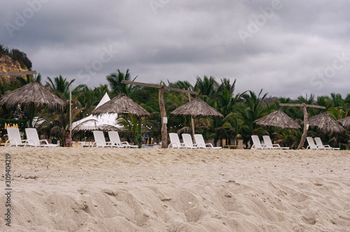 sunbeds in the sand, next to huts, during a great day at tropical beach