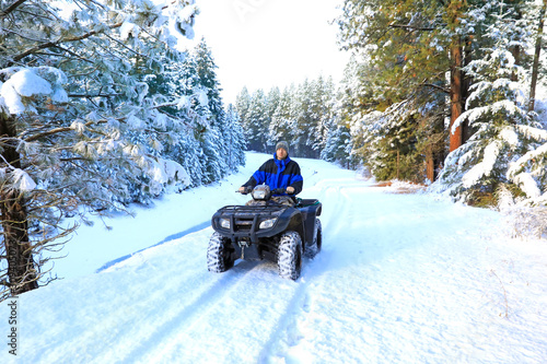 Man riding snowmobile or fourwheeler on the country side trail near water canal.