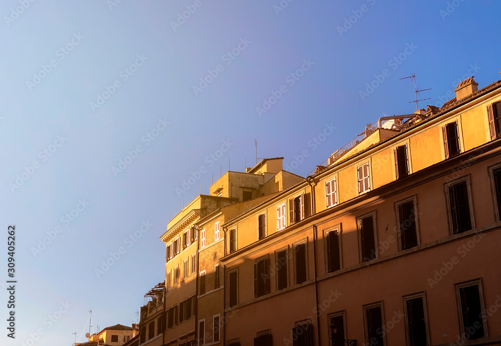 the facades of ancient buildings in Rome illuminated by the light of the sun at dawn