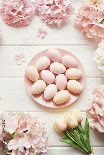 Spring and Easter holiday greeting card concept. Pink and white hydrangeas, yellow tulips with pink eggs. Colorful easter eggs and branch with flowers. Postcard Template. Copy space. Flat lay.