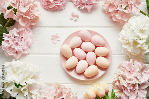 Spring and Easter holiday greeting card concept. Pink and white hydrangeas, yellow tulips with pink eggs. Colorful easter eggs and branch with flowers. Postcard Template. Copy space. Flat lay.