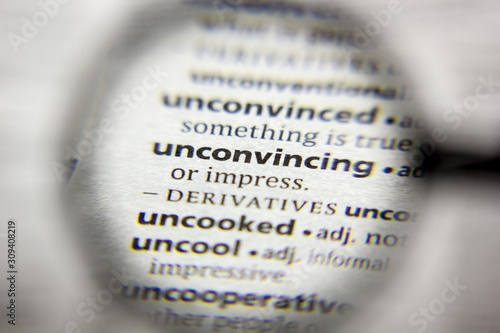 The word or phrase Unconvincing in a dictionary. photo