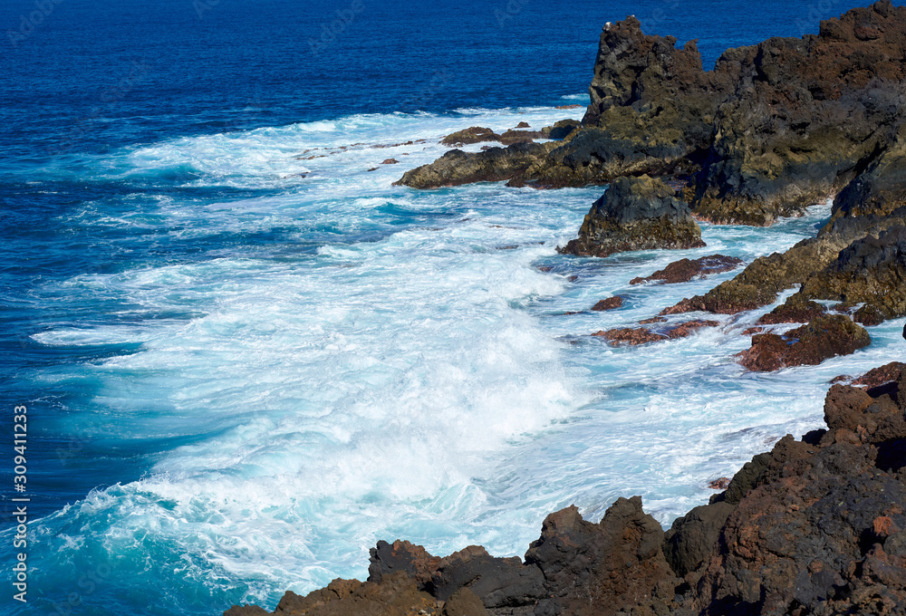 Obraz premium Deep blue waves, white foam and spray. Canary Islands. Lanzarote, volcanic island. The magnificent coast of the Atlantic Ocean. February 2019.