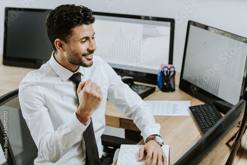 high angle view of bi-racial trader showing yes gesture and looking at computer