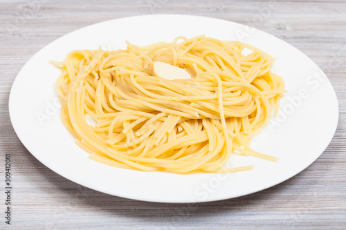pasta with butter on white plate on gray table