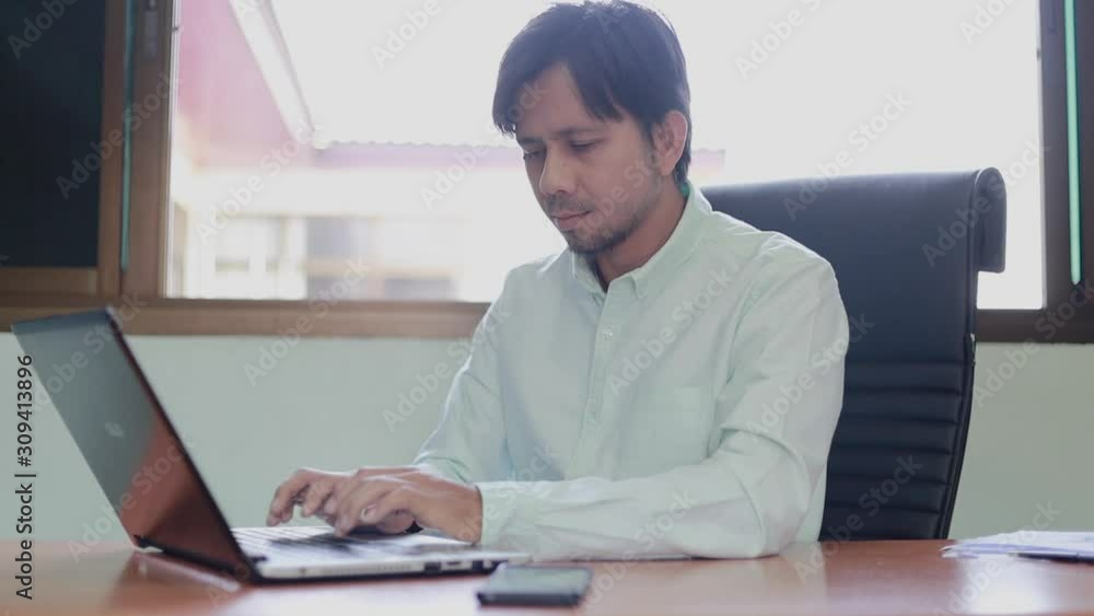 Young asian business man working with laptop documents sitting at office desk, financial analyst Young asian business man working with laptop documents sitting at office desk, financial analyst