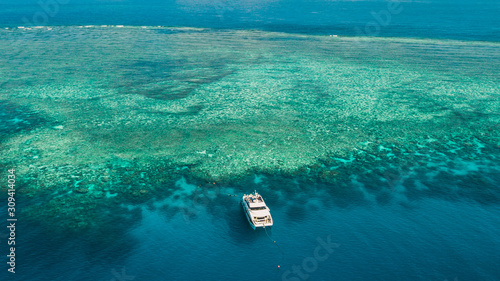AUSTRALIA, Cairns: view of the Great Barrier Reef from above. Dive boat moored close to the reef, divers and snorkelers around.