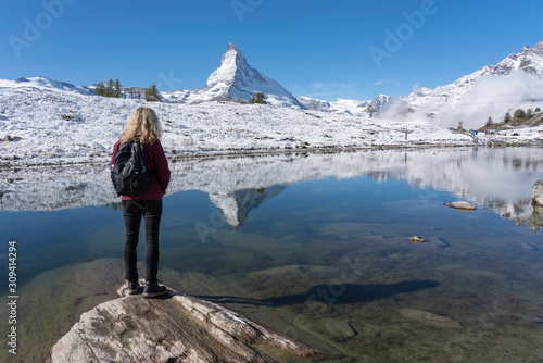 Single blond caucasian middle-aged woman traveling through Switzerland admiring the Matterhorn and its reflection in Lake Leisee photo
