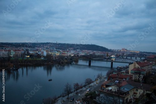  Winter panorama from Vysehrad Castle to the evening city of Prague, residential areas, the Vltava River, moorings with boats and boats and city transport. © Olena