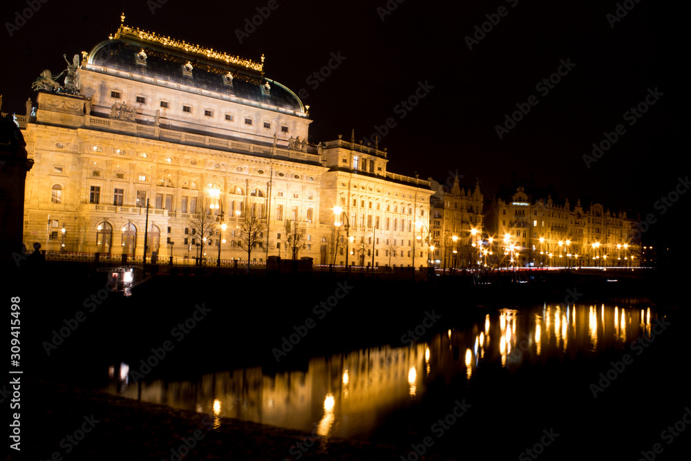 Fototapeta premium Night city landscape and panorama in the bright evening lights of the Czech capital Prague overlooking the Vltava River.